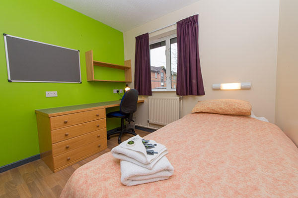 A bedroom inside ϲʹ accommodation. There is a single bed, a large pin board, desk, chest of drawers and a window in the room.